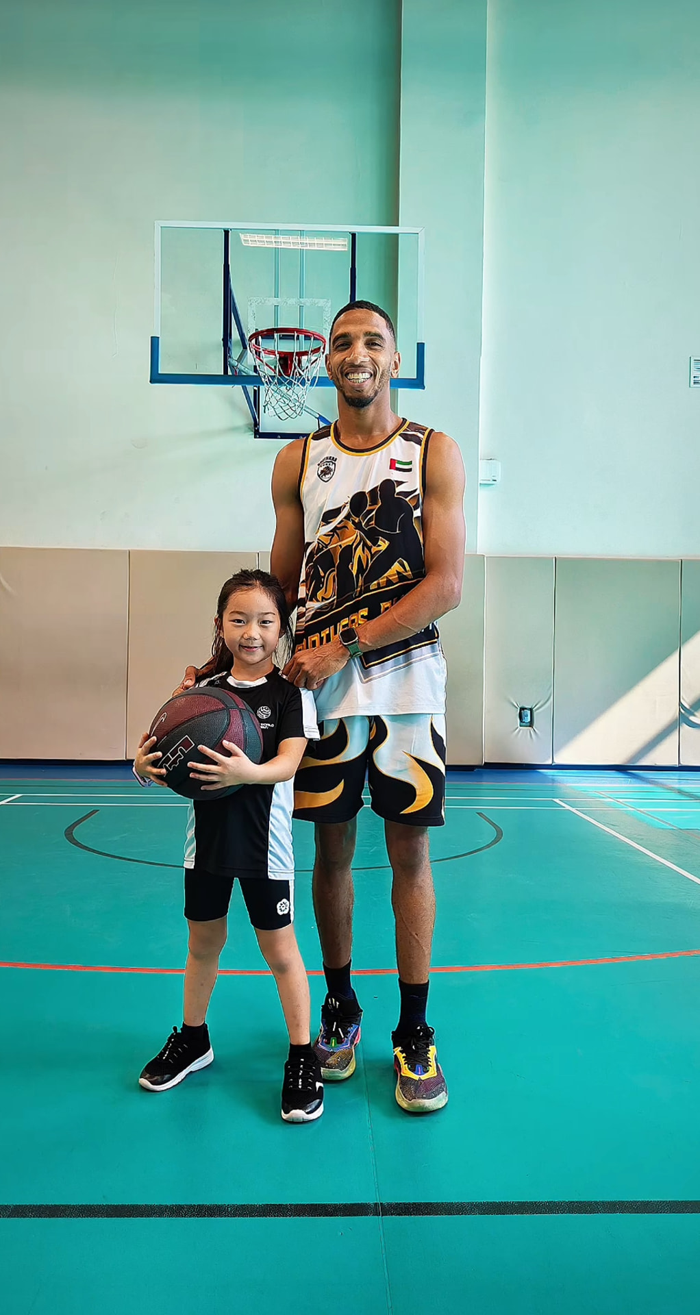 Coach with a young academy player holding a basketball